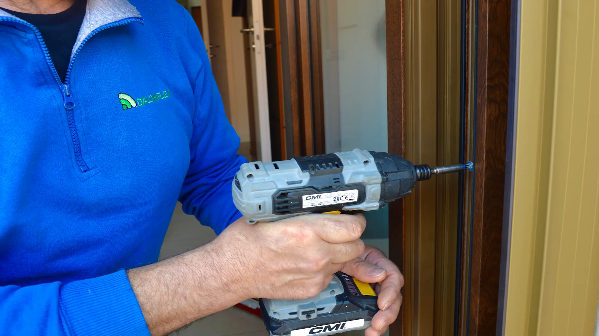 Tecnico Dalonflex con la polo aziendale avvita il telaio di una zanzariera su un serramento